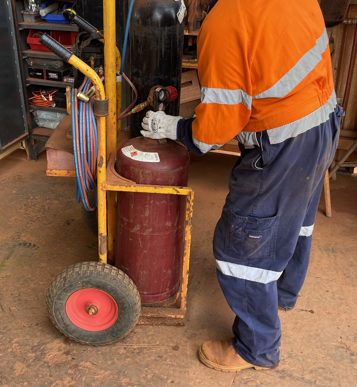 Boilermaker handling a heavy gas cylinder in a workshop
