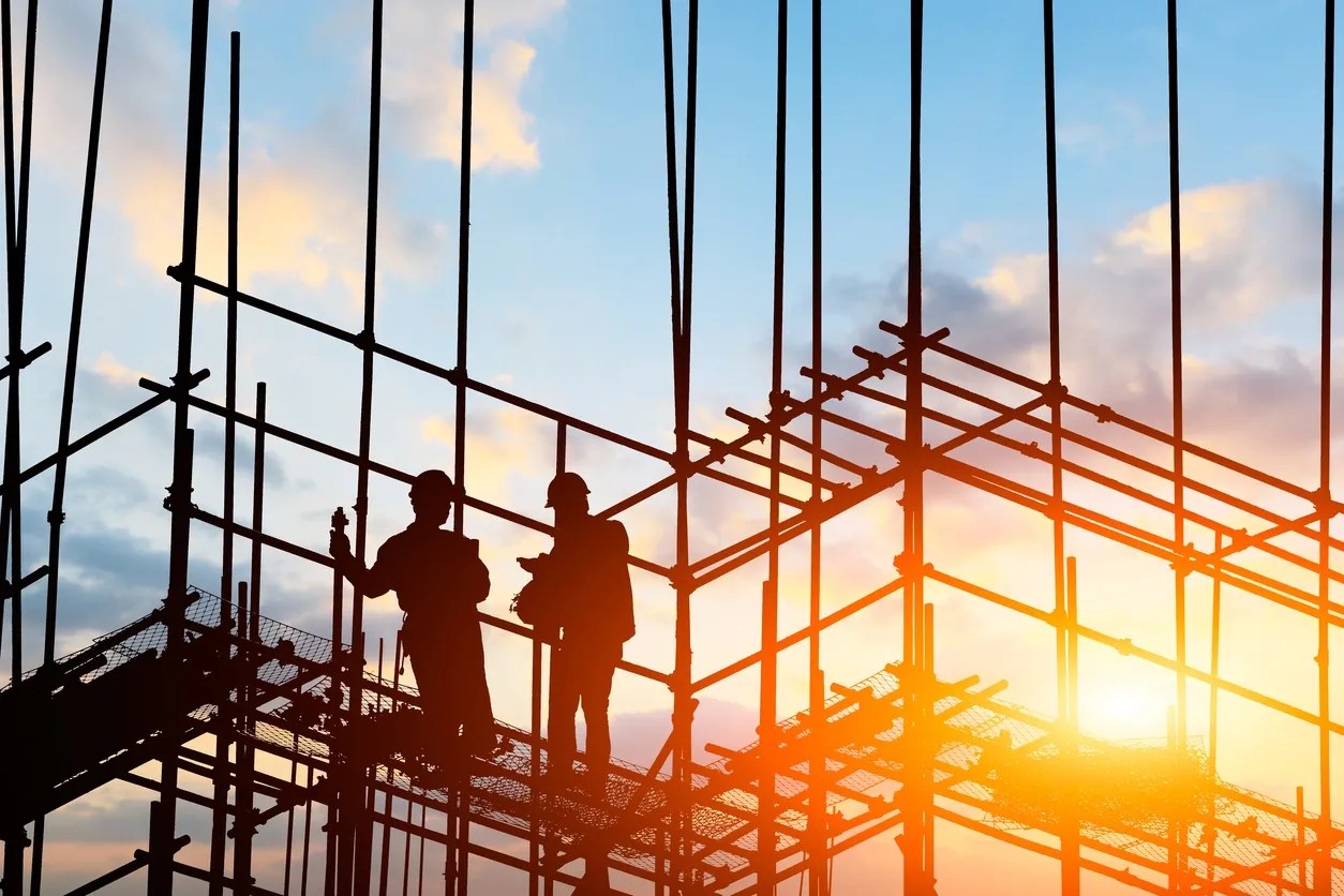 Construction workers on scaffolding at sunset