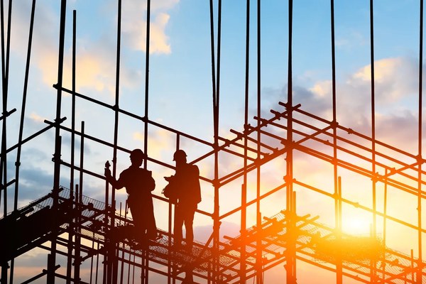 Construction workers on scaffolding at sunset