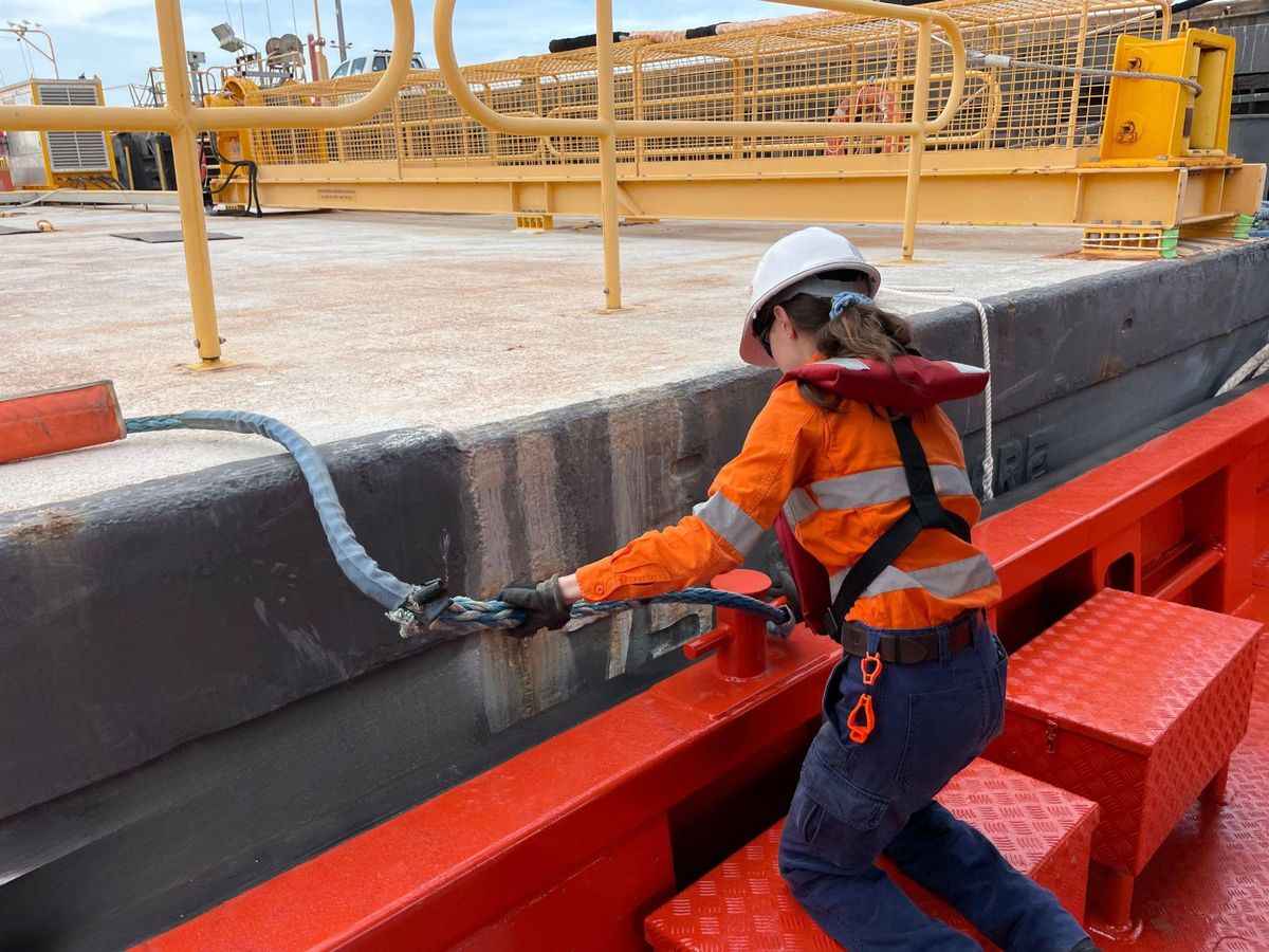 Worker handling a heavy mooring line on a vessel deck