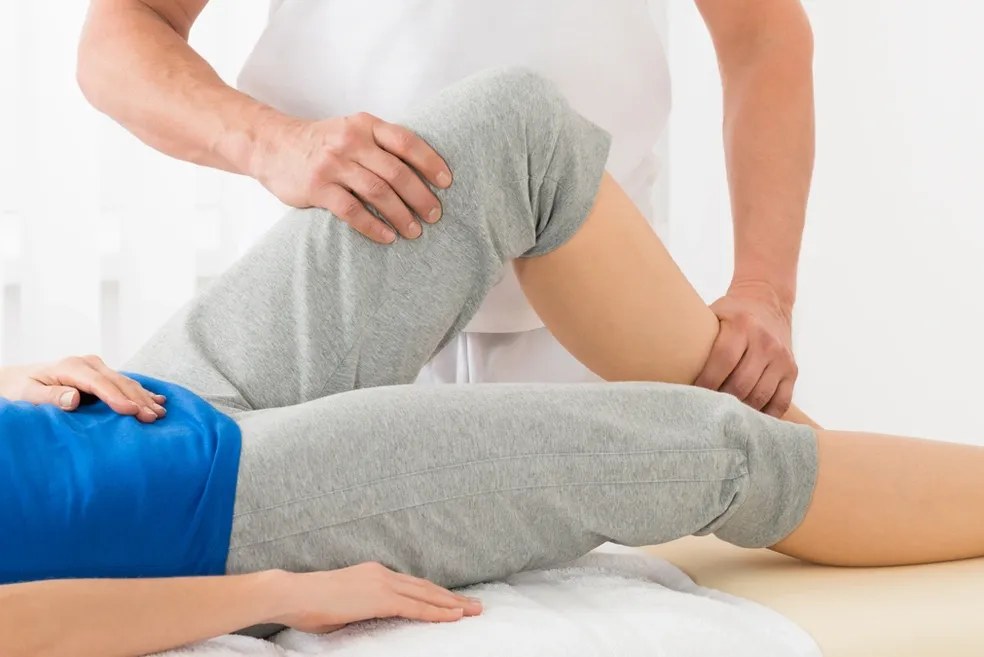Physiotherapist mobilising a patient’s hip and knee on a treatment table